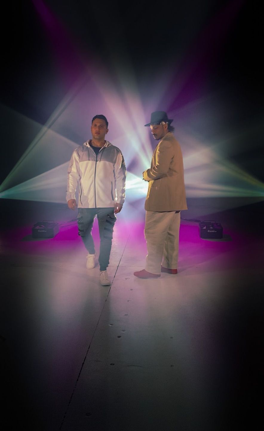 Two performers in white suits crossed by stage lasers