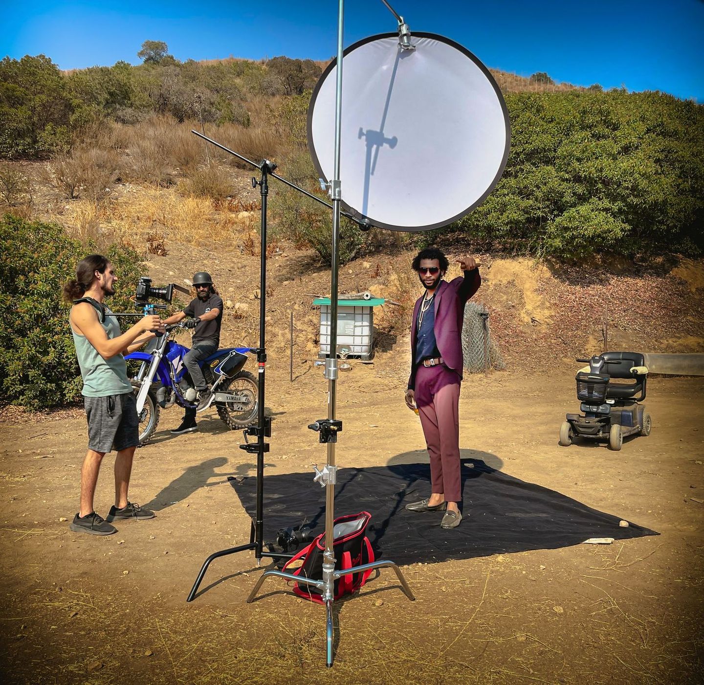 Film crew with camera and bounce board on a hillside set