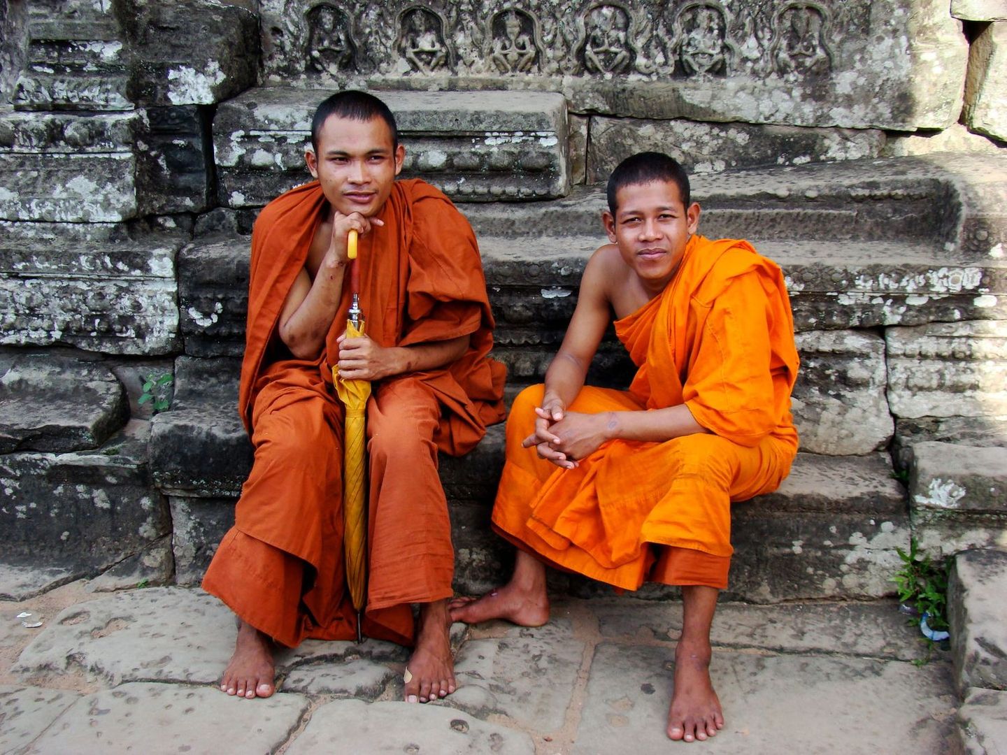 Two monks in orange robes seated in conversation
