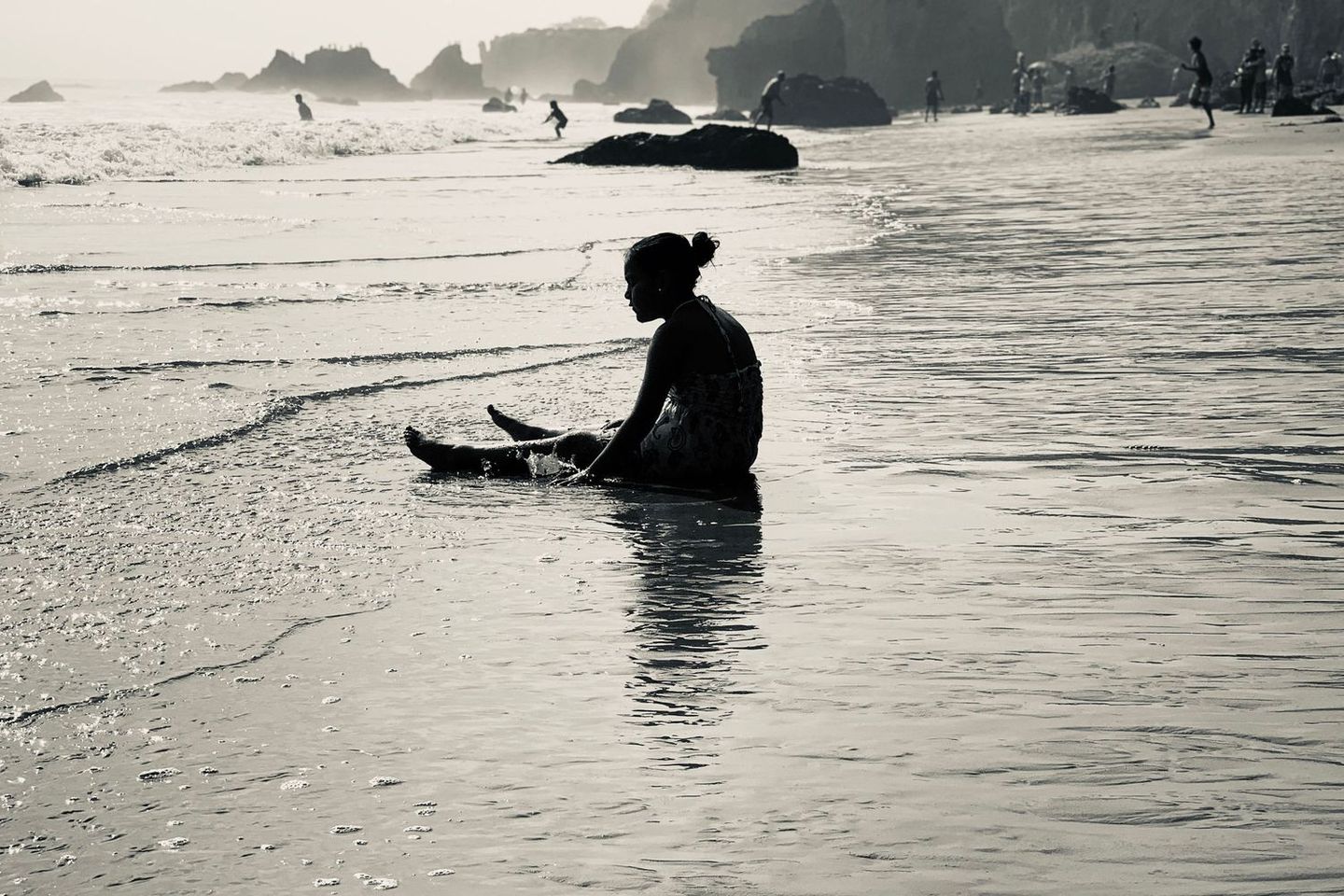 Black and white image of a surfer sitting in the ocean