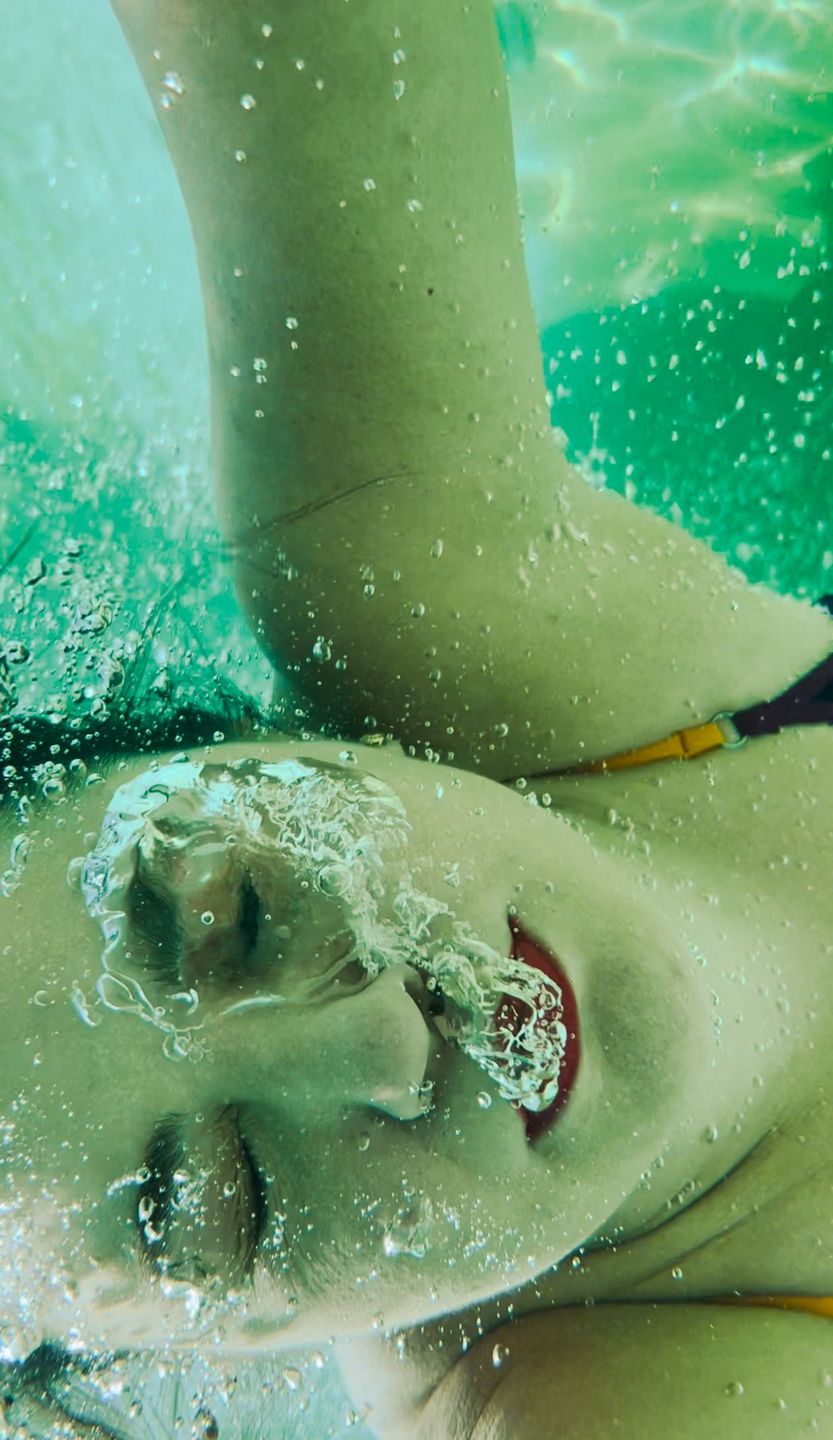 Underwater portrait in turquoise water, face breaking the surface