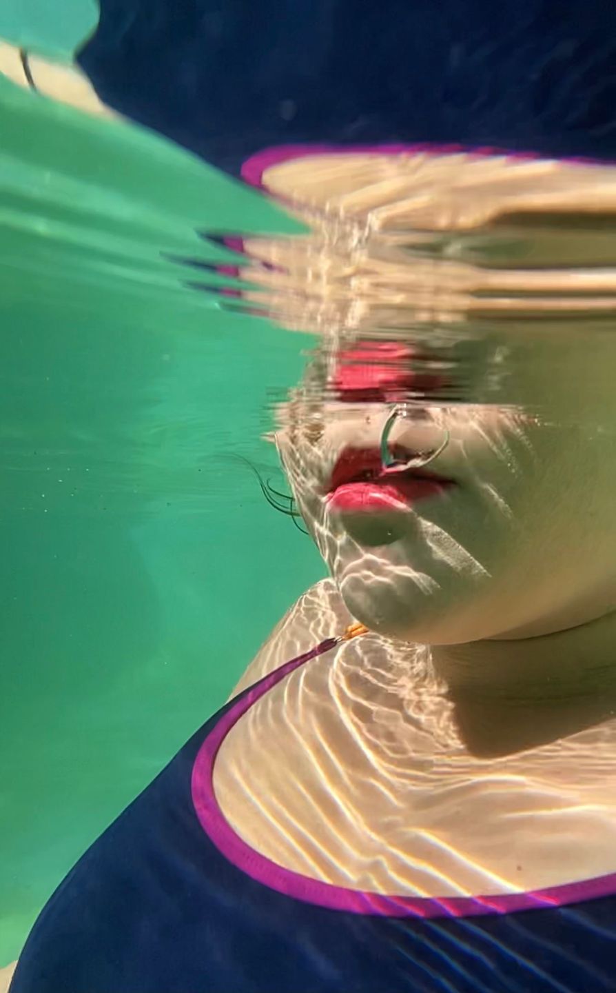 Swimmer in goggles beneath rippled turquoise water