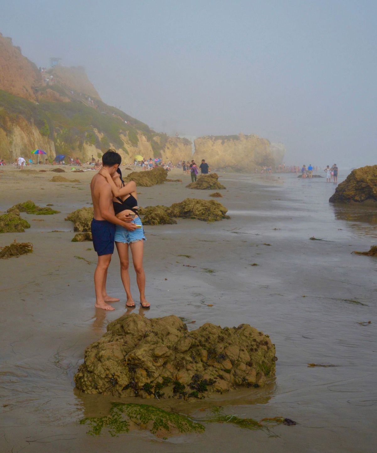 Family wading at the shoreline of a rocky beach