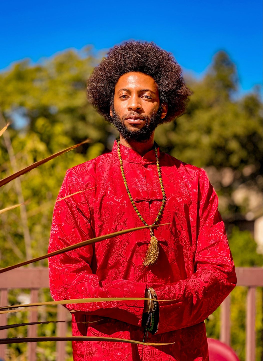 Portrait of a man in a red jacket with an afro, lit by warm golden light