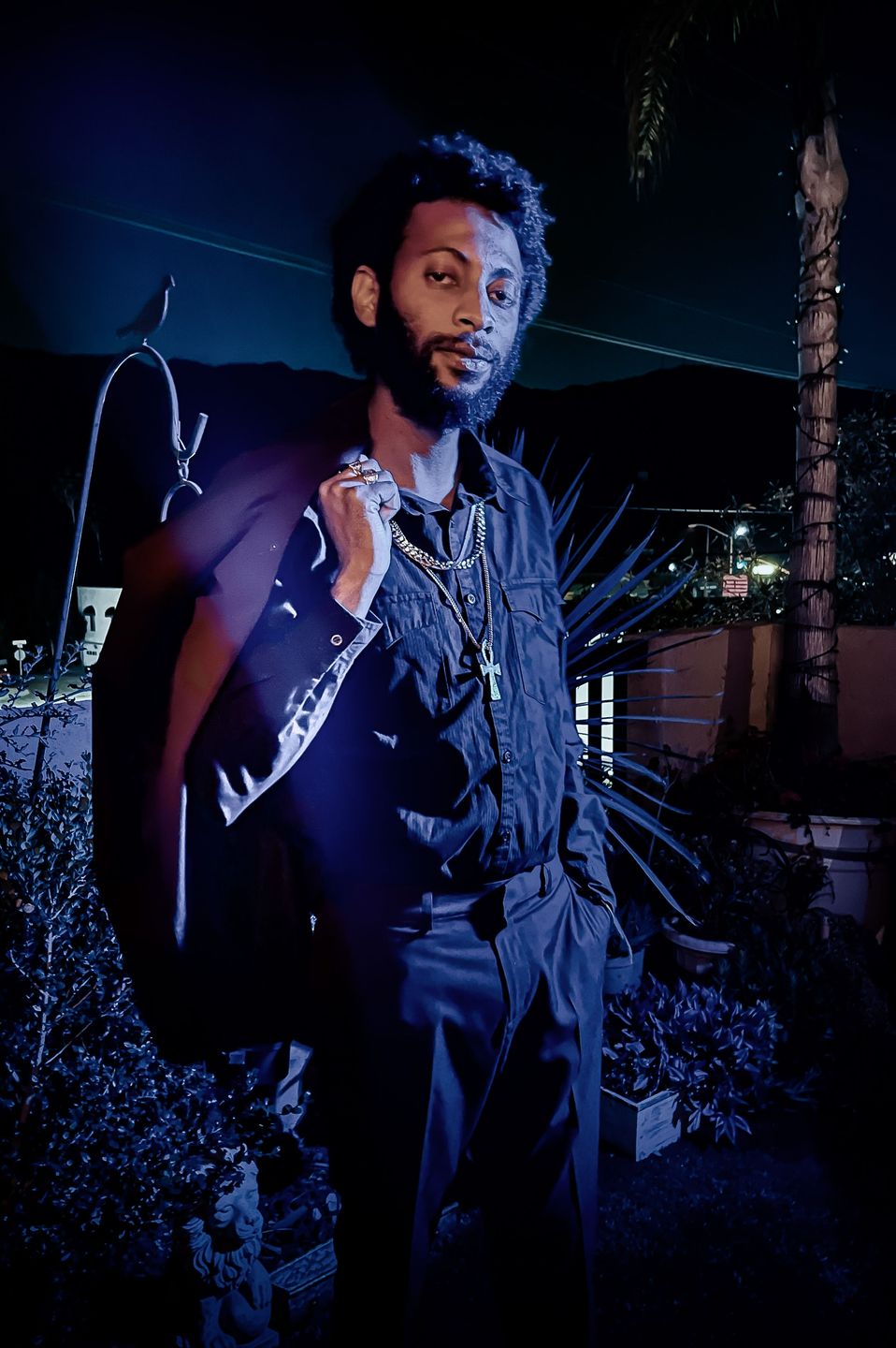 Night portrait of a man with a jacket slung over his shoulder under purple light