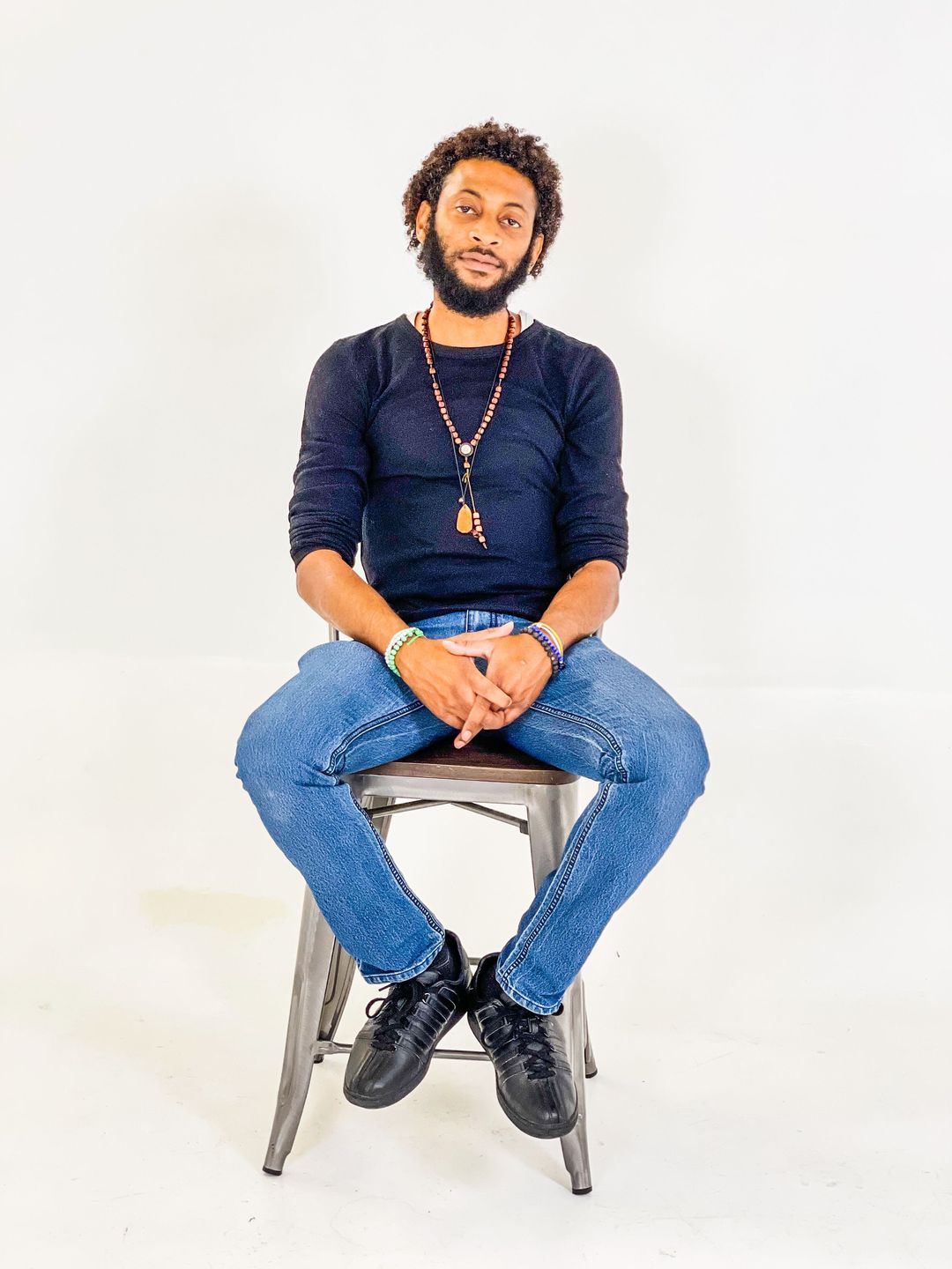 Studio portrait of a man seated on a stool against a white backdrop