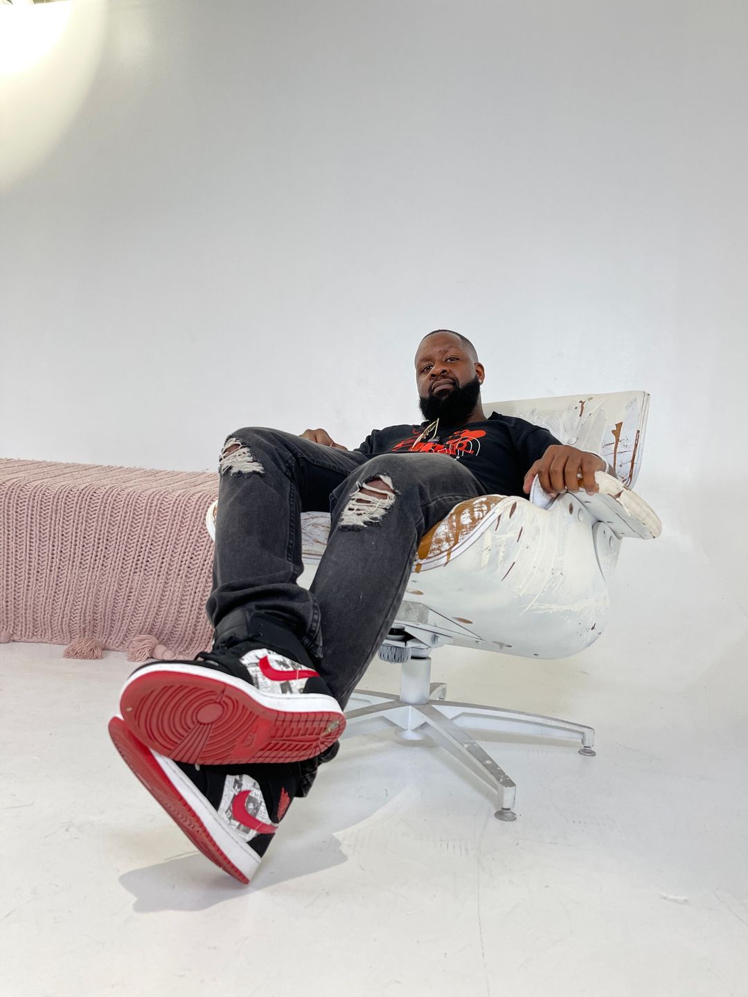 Man reclining on a white sofa in red sneakers