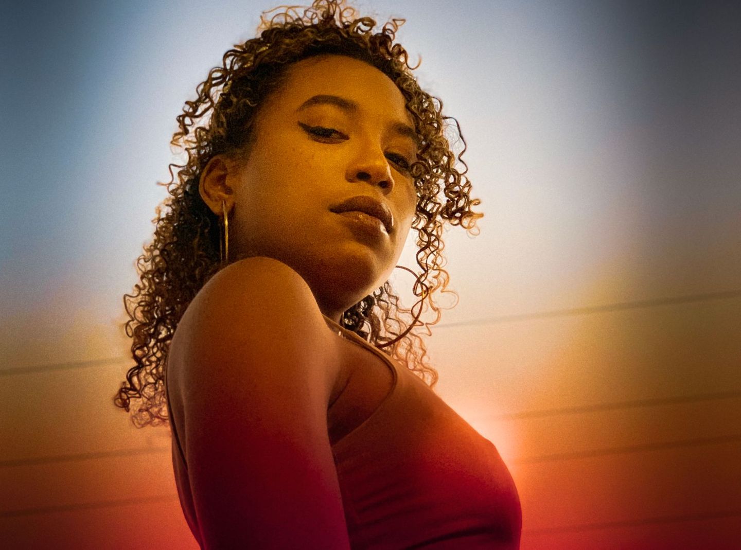 Warm portrait of a woman with curly hair looking over her shoulder
