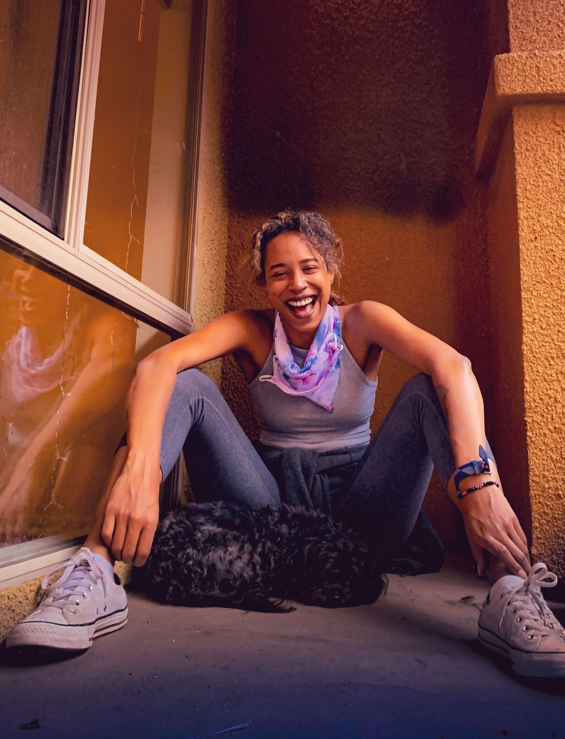 Woman laughing in a doorway with her dog, in sneakers