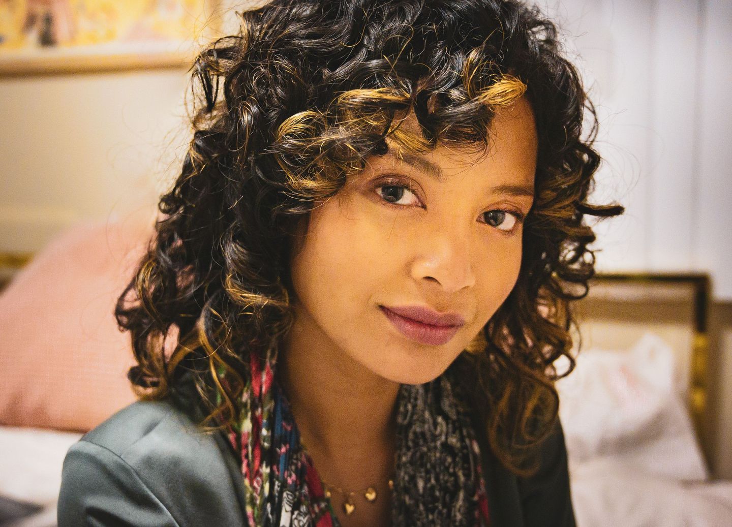 Portrait of a woman with curly hair in a blazer, lit by soft window light