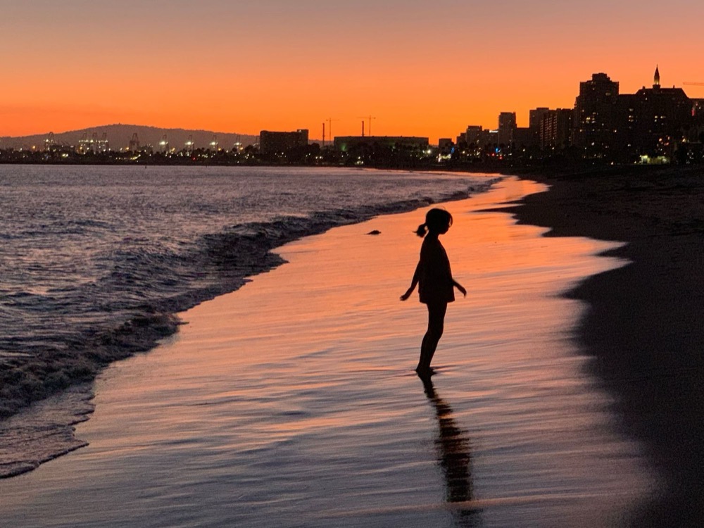 Child silhouetted against the ocean at sunset