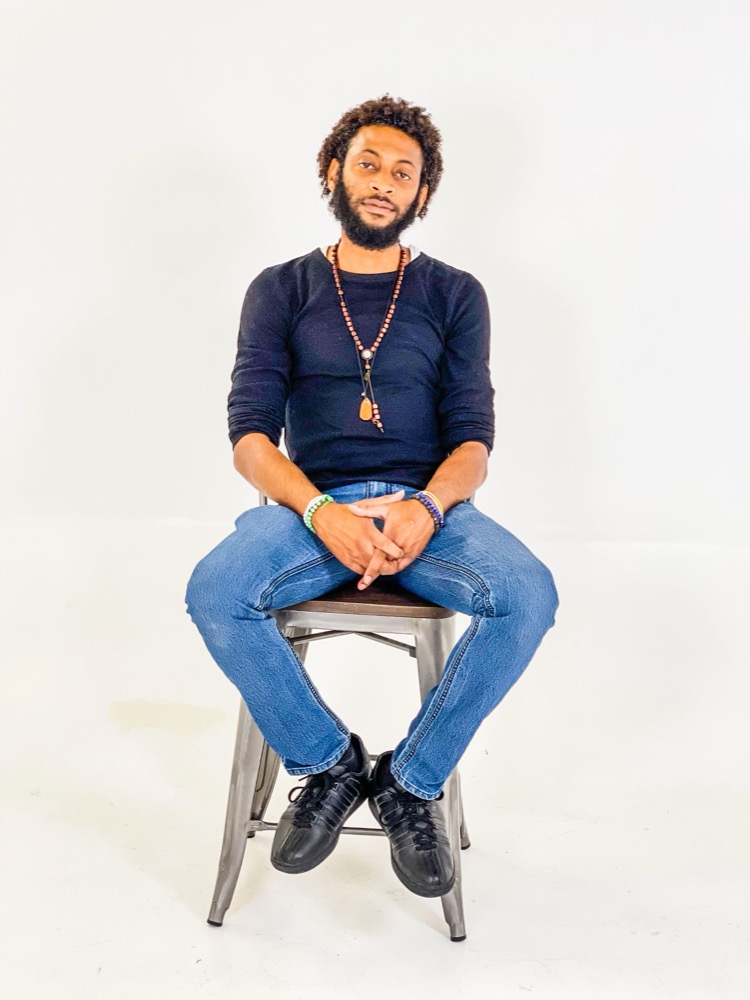 Studio portrait of a man seated on a stool against a white backdrop