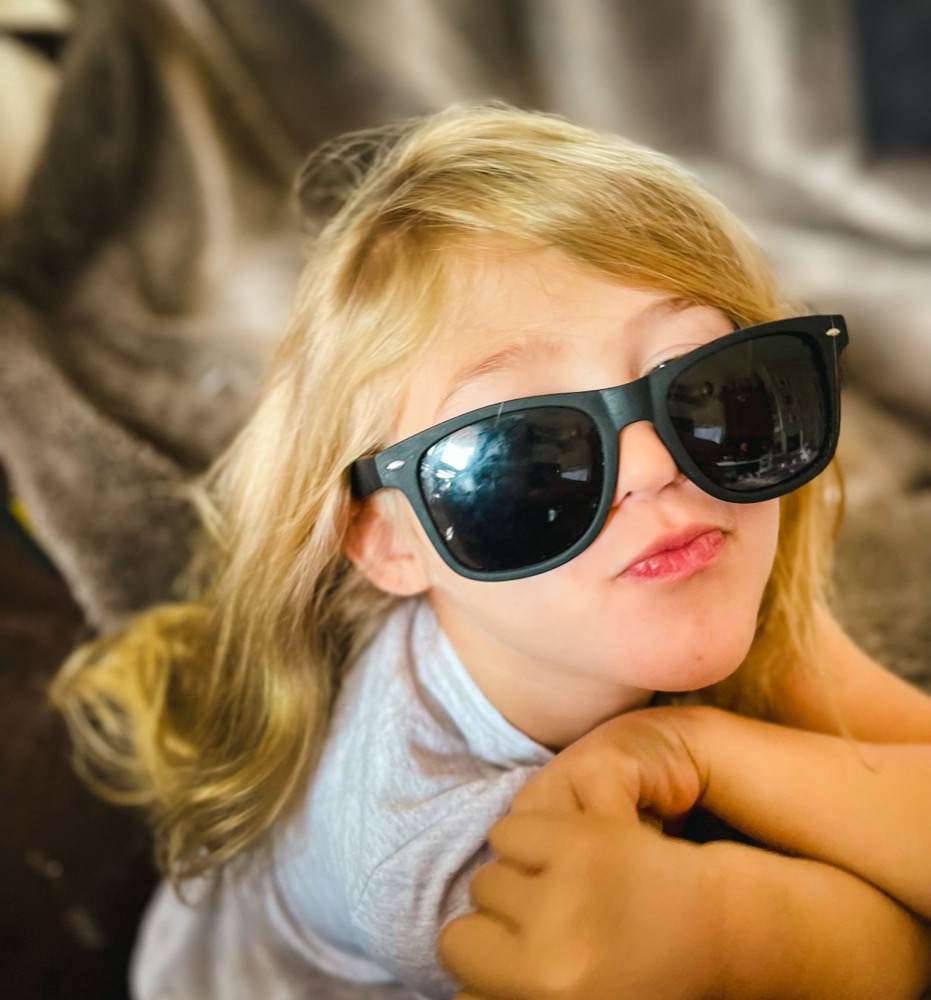 Toddler in oversized sunglasses striking a pose
