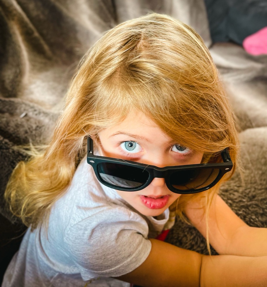 Toddler in oversized sunglasses laughing outdoors